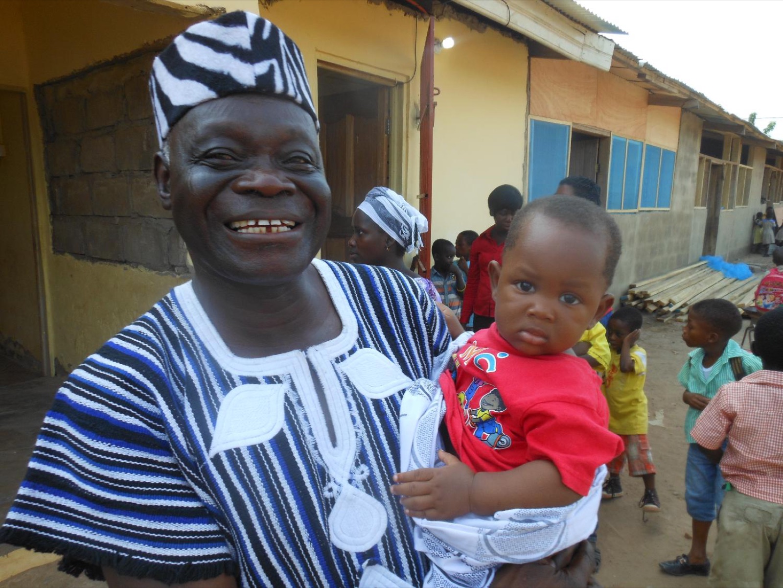 A smiling Emperor Academy staff member holding a young child