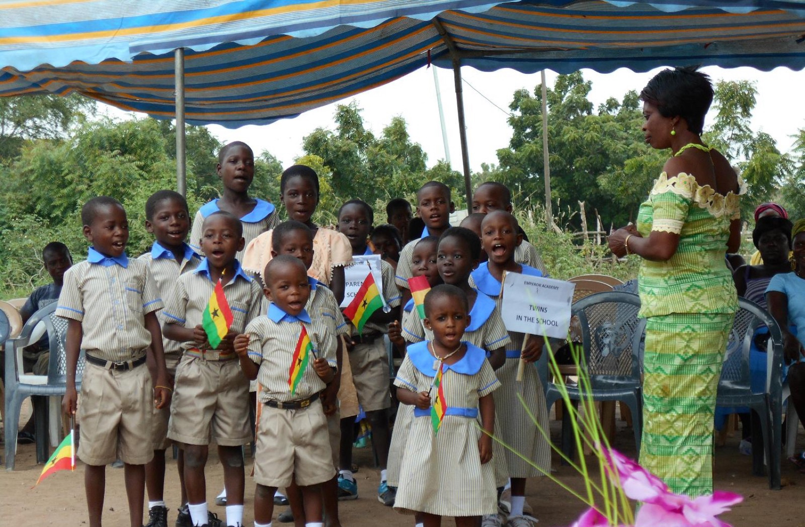 Emperor Academy students in uniform holding Ghana flags at a school ceremony
